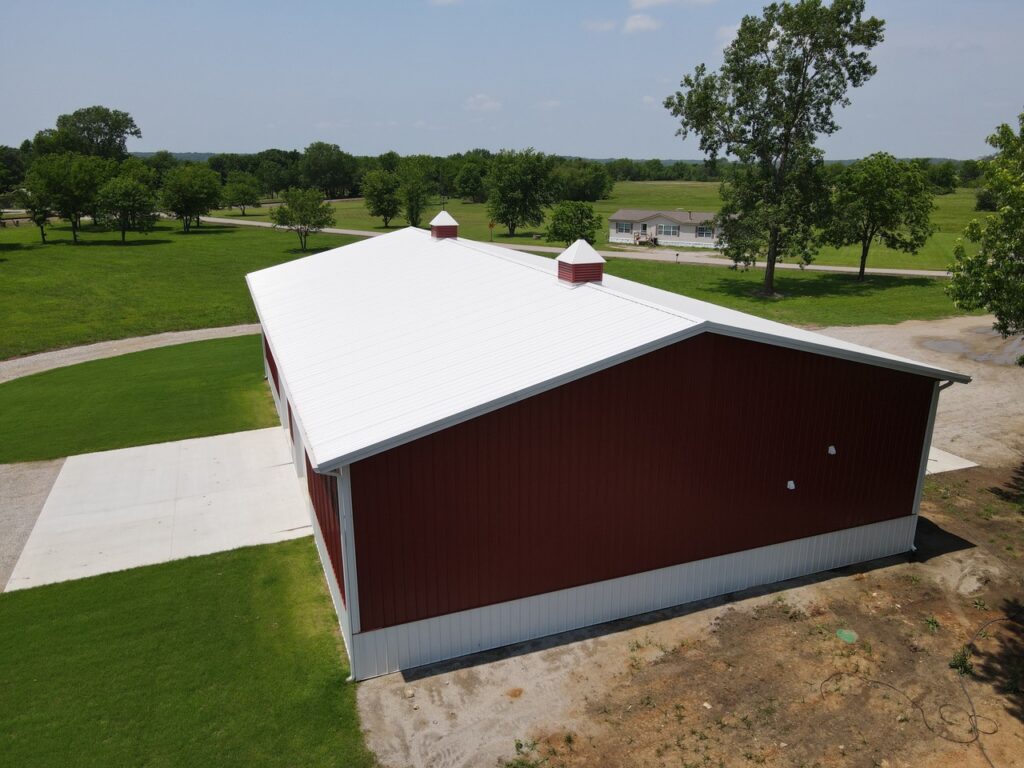 Crimson Buildings AERIAL SIDE VIEW OF A RED POLEBARN WITH ROCK DRIVE