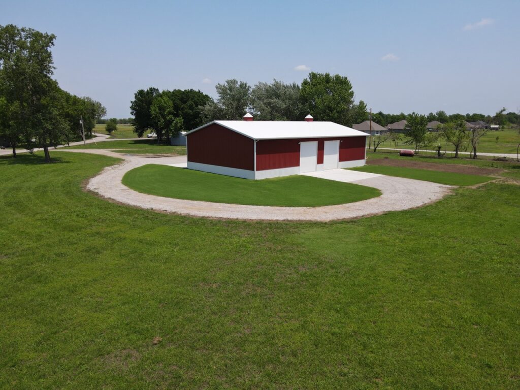 Crimson Buildings AERIAL VIEW OF A RED POLEBARN WITH ROCK DRIVE